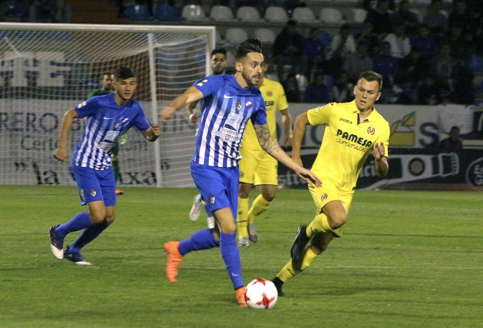 El centrocampista del Ponferradina Iago Díaz (c) con el balón ante el delantero ruso del Villarreal, Denis Dmitriyevich Cherychev (d).