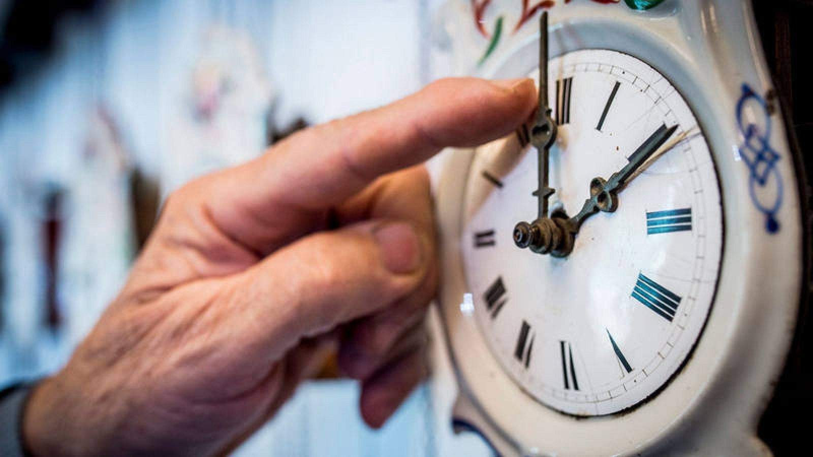 Un hombre ajustando la hora en su reloj de bolsillo. 