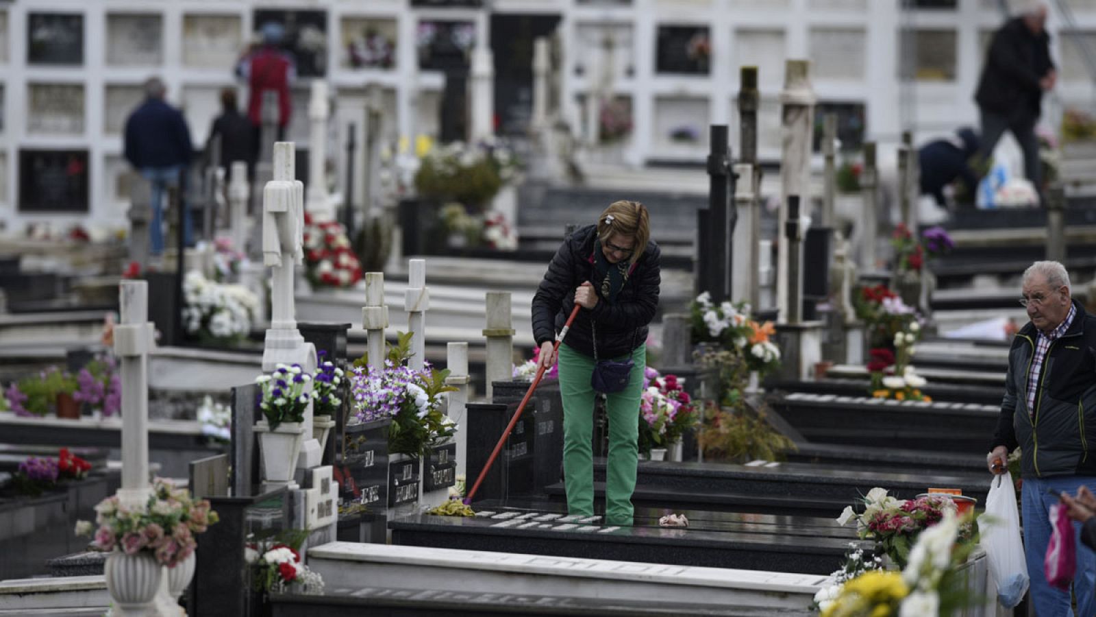 Una mujer limpia una tumba en un cementerio de Oviedo