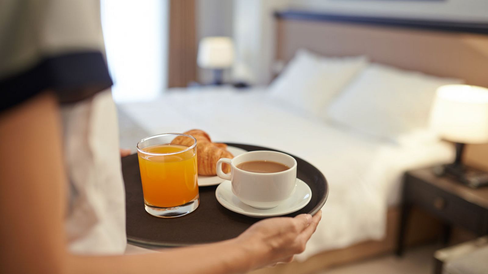 Una camarera sirve un desayuno en una habitación de hotel