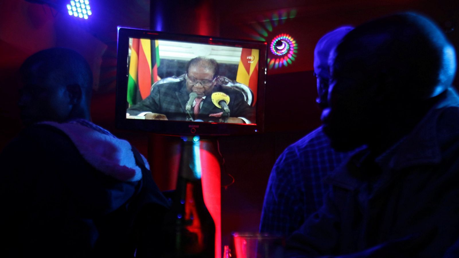 La gente sigue la alocución del presidente de Zimbabue, Robert Mugabe, en un bar de Harare