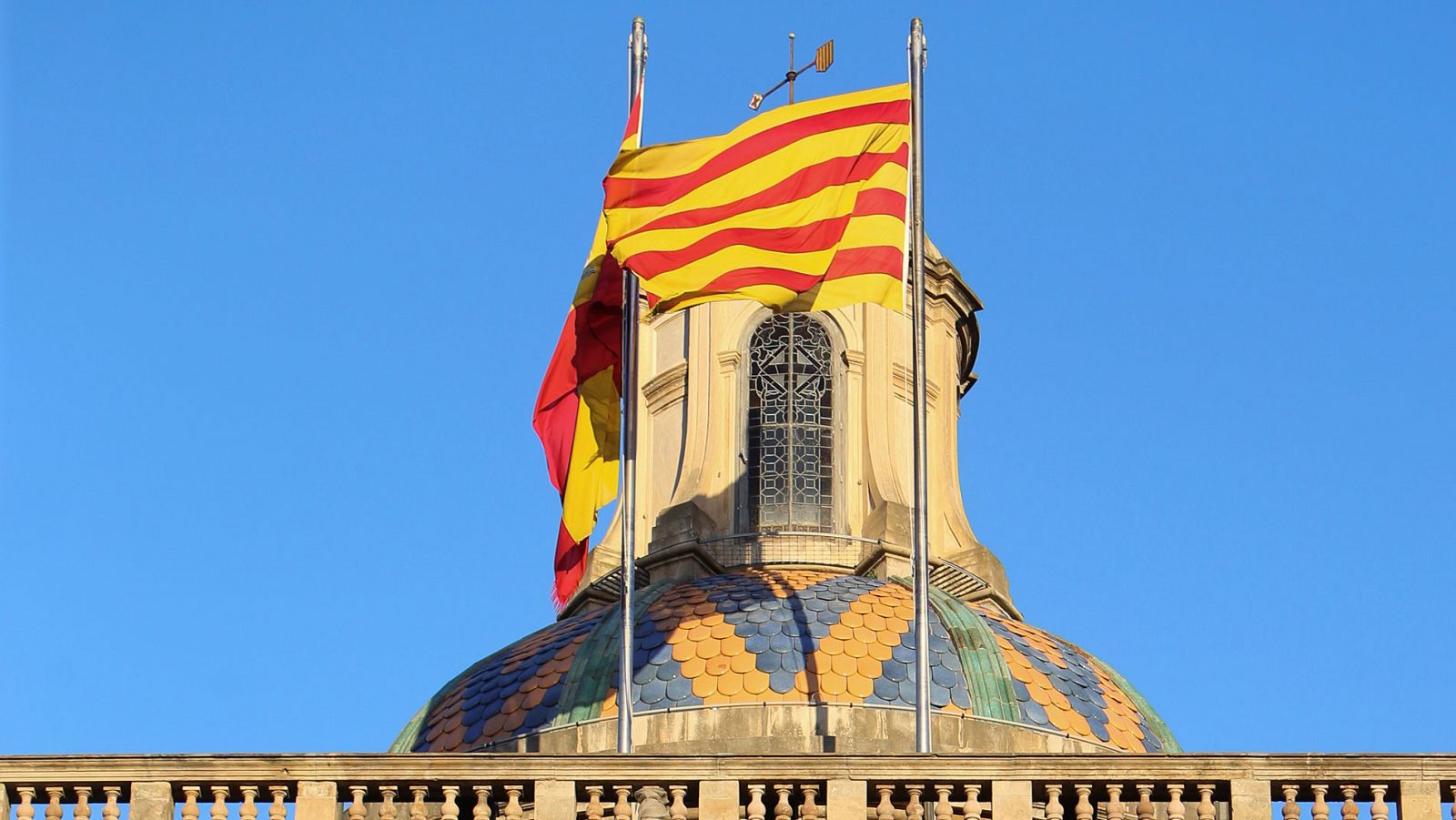 Bandera catalana y española ondeando en la fachada de la Generalitat