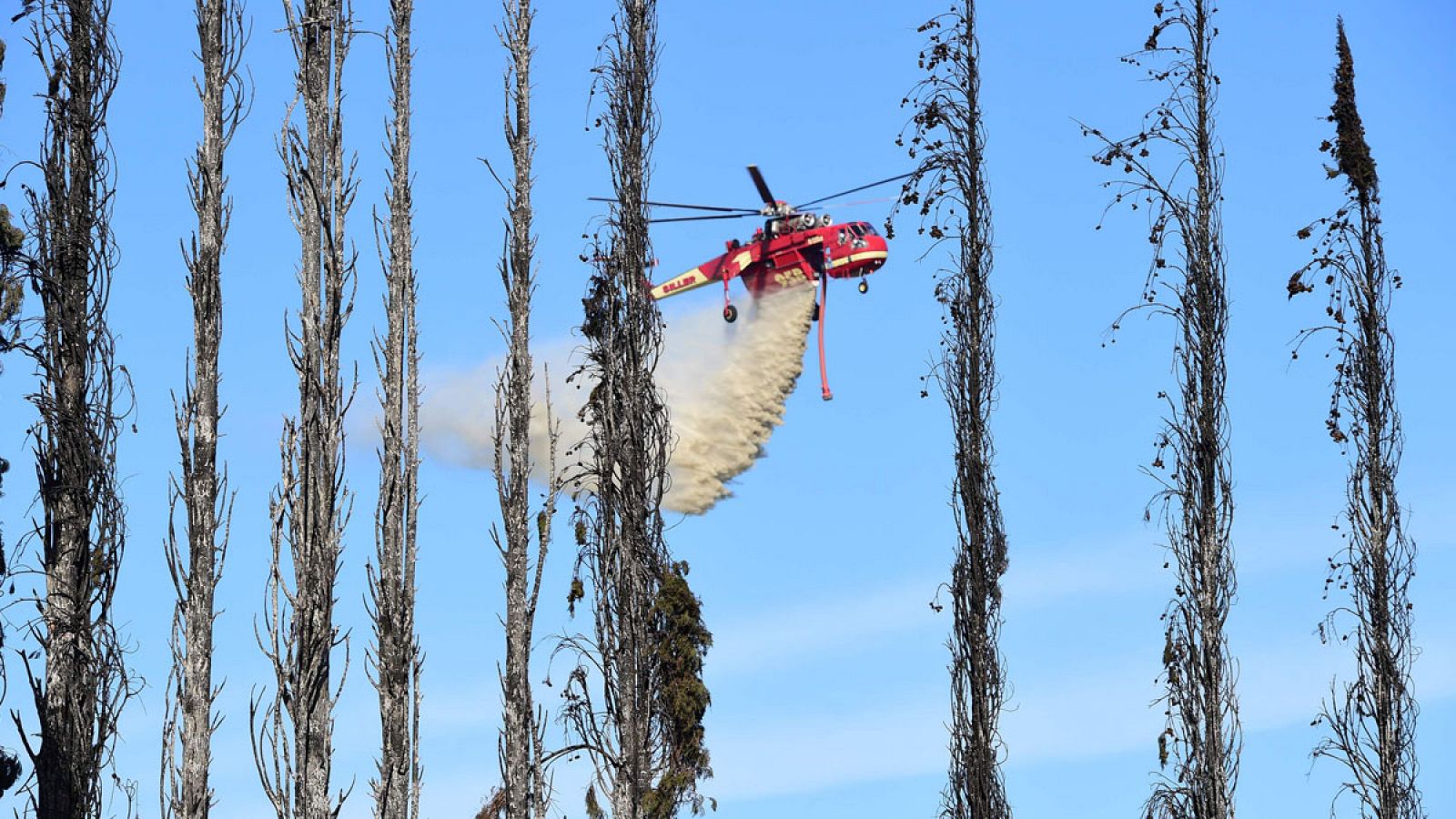 Imagen de un helicóptero arrojando agua sobre granjas y residencias afectadas por los incendios en California.