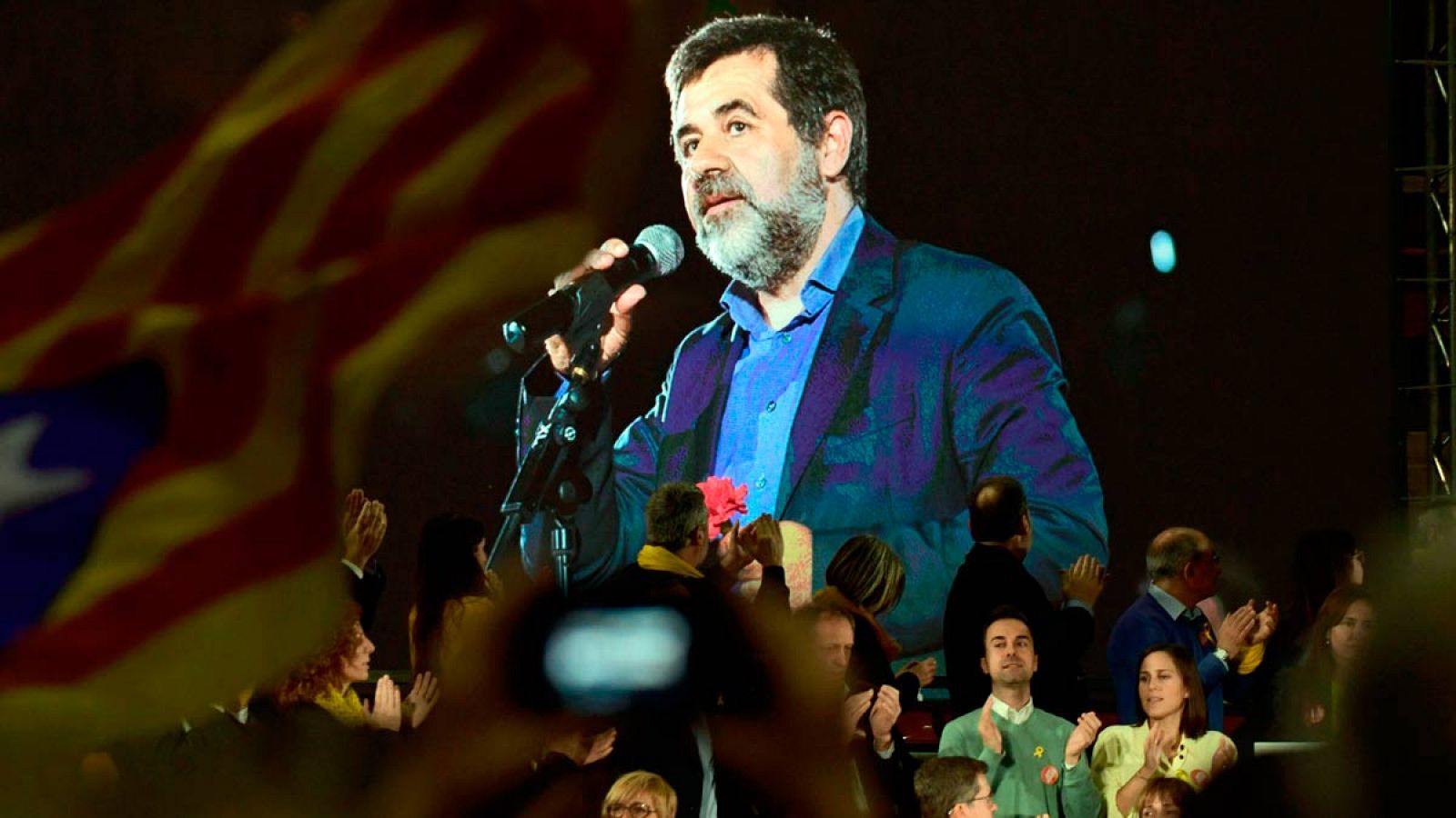 Jordi Sànchez interviene a través de un mensaje telefónico en un mitin.