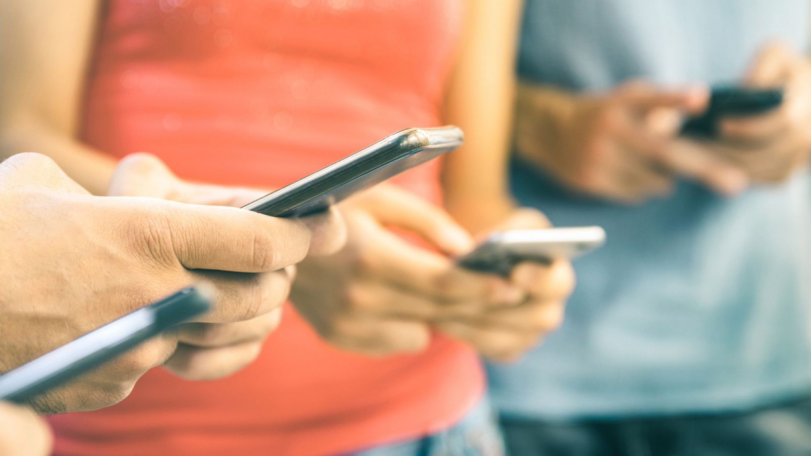 Multicultural friends using smartphone outdoors - People hands addicted by mobile smart phone - Technology concept with connected men and women - Shallow depth of field on bright vintage filtered tone