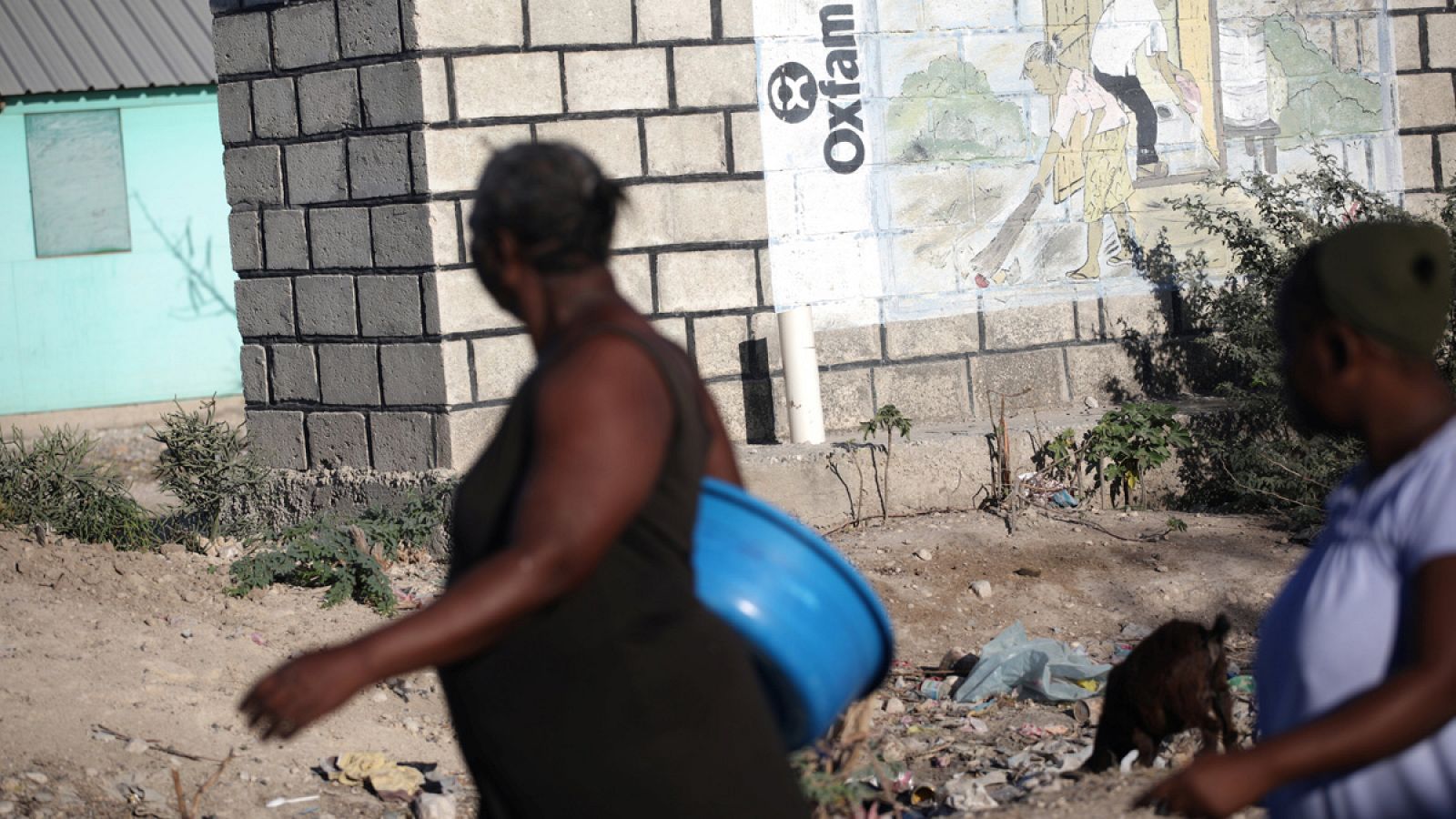 Gente camina por delante de un logo de Oxfam en Corail, un campo para desplazados por el terremoto de 2010 en las afueras de Puerto Príncipe