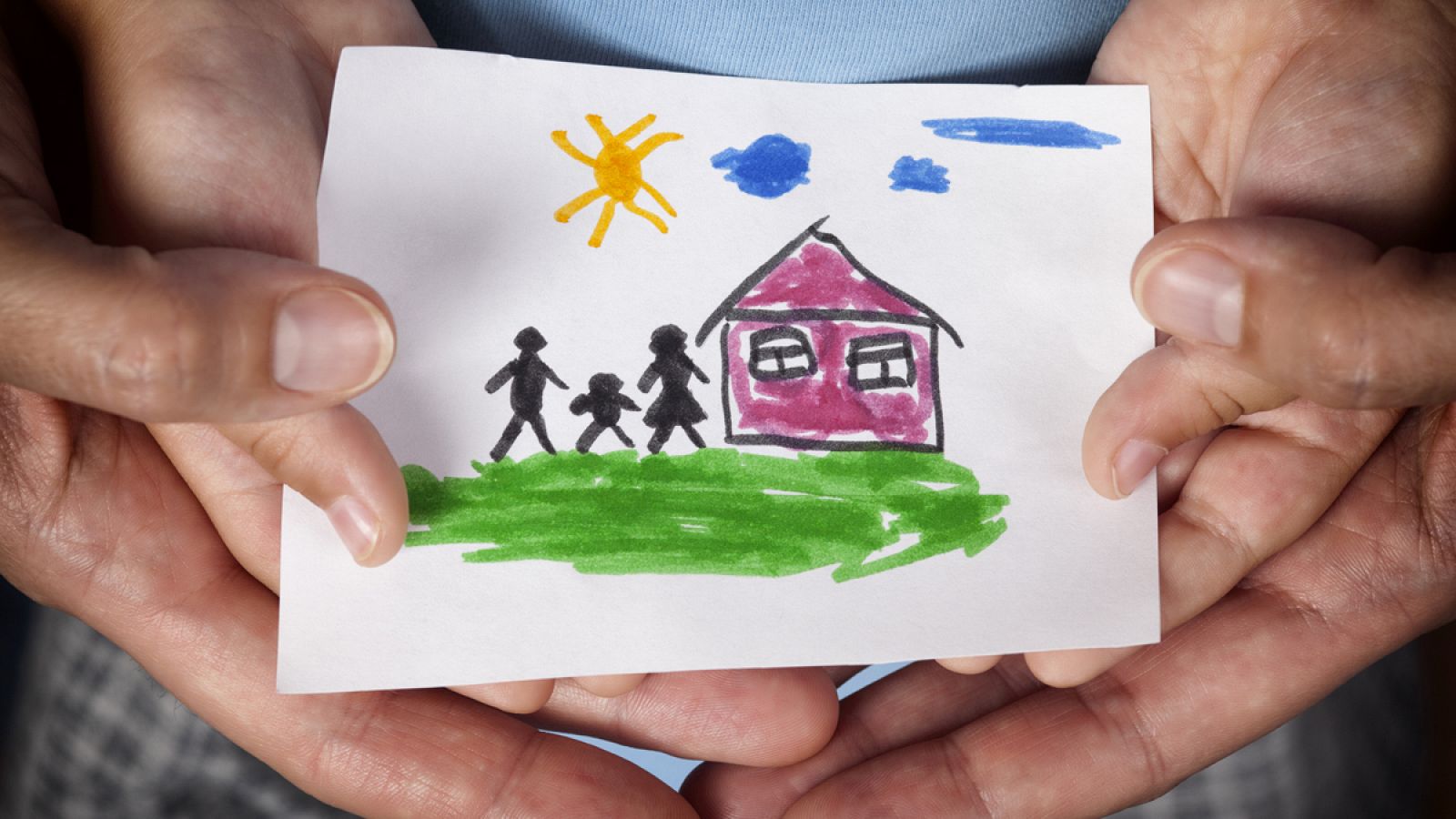 Un niño y su madre sostienen un dibujo que representa una familia