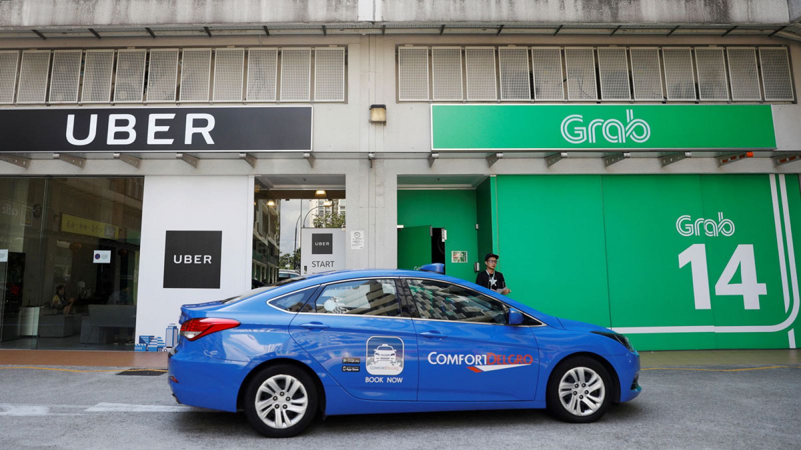 Un taxi pasa delante de las oficinas de Uber y Grab en la ciudad de Singapur