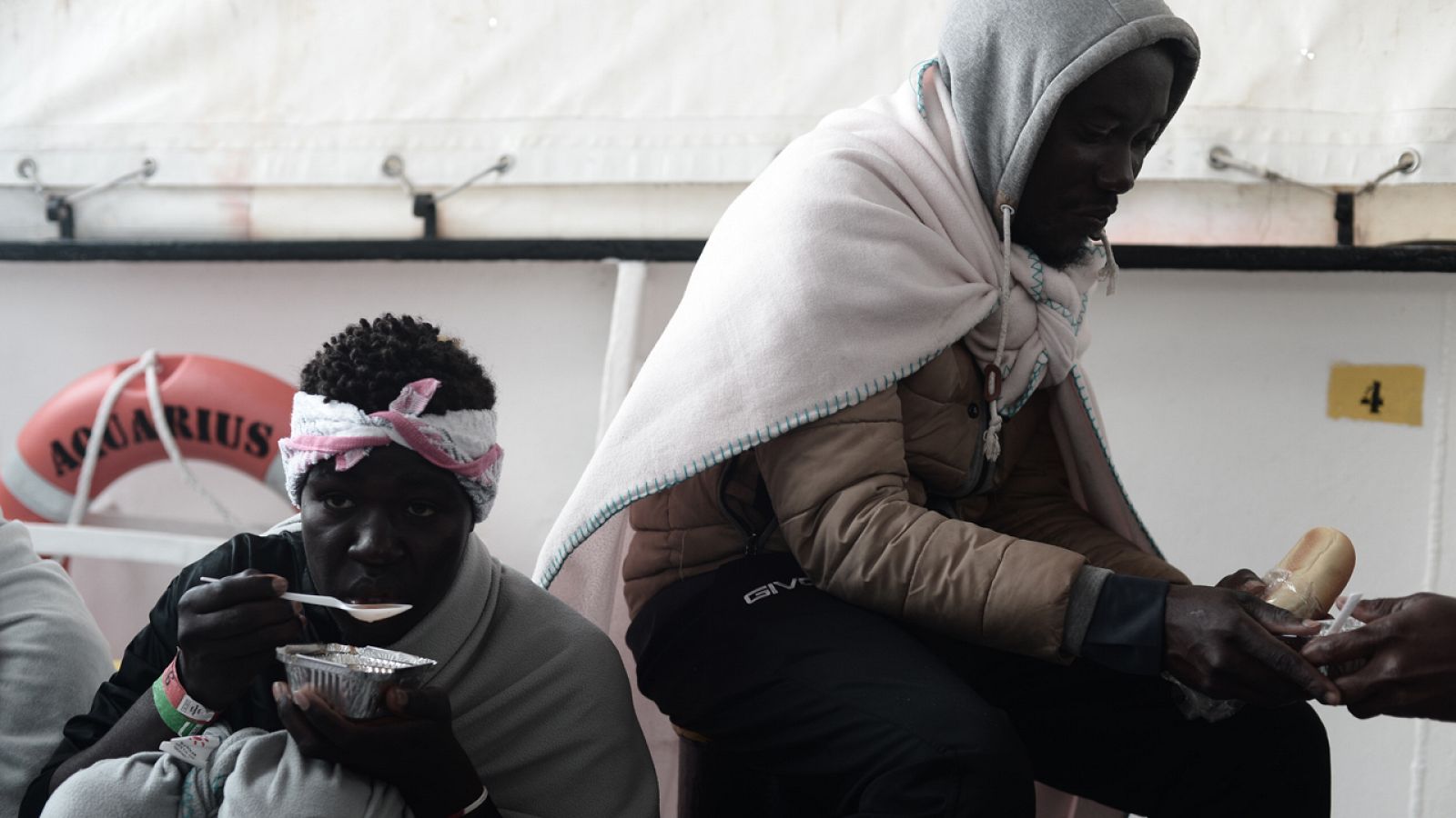 Dos migrantes desayunan en el Aquarius