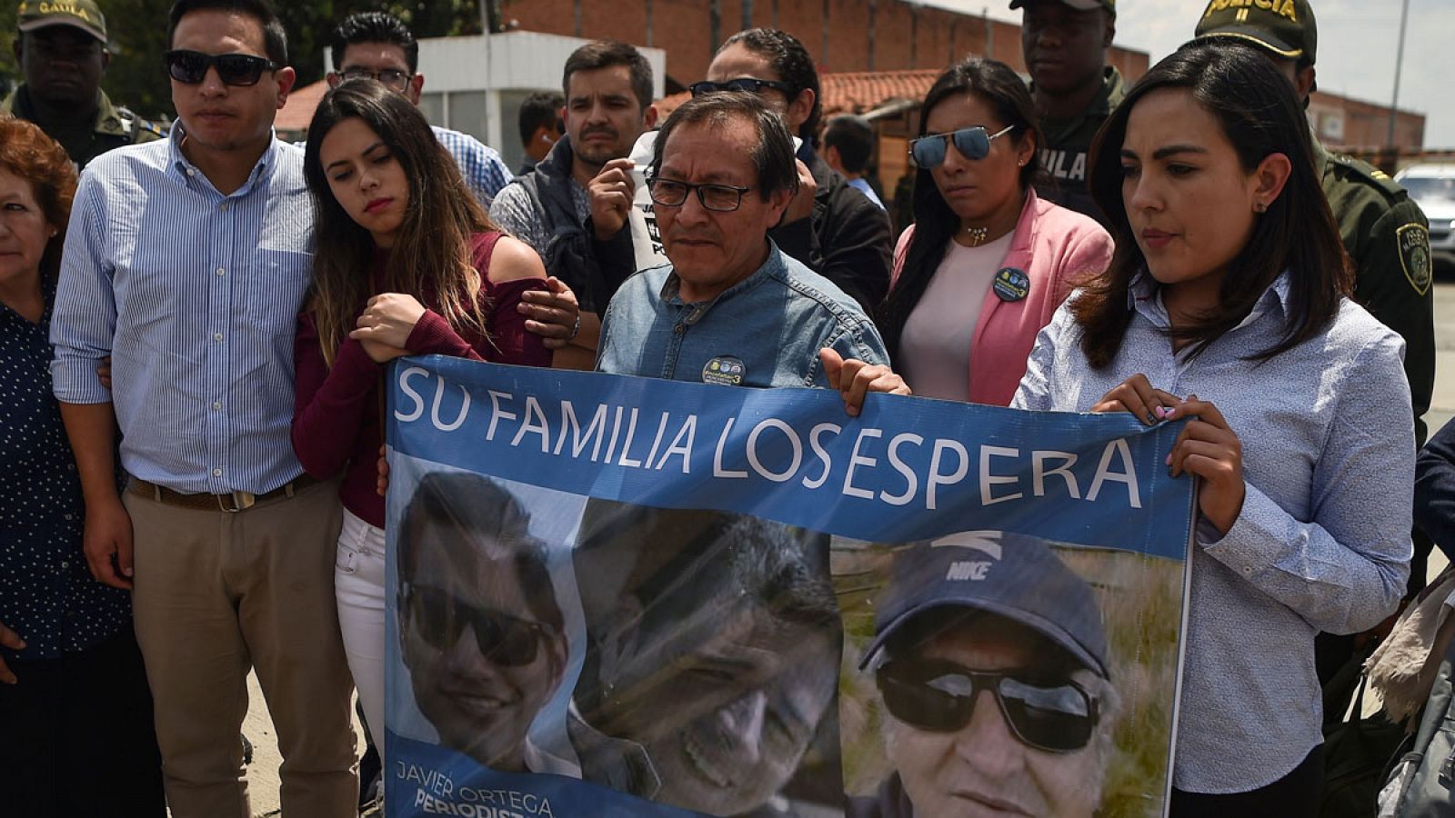 Familiares del periodista Javier Ortega, el fotógrafo Paúl Rivas y el conductor Efraín Segarra con una pancarta con sus rostros.