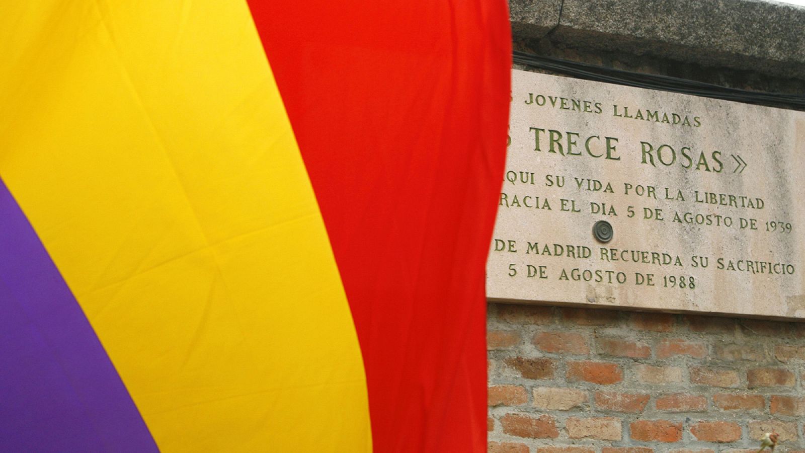 Una bandera republicana ondea junto a la placa que recuerda en el cementerio de la Almudena a las Trece Rosas