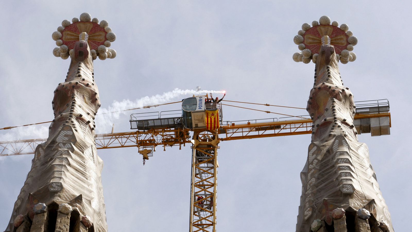 Dos jóvenes encaramados a una grúa en la Sagrada Familia despliegan una bandera independentista