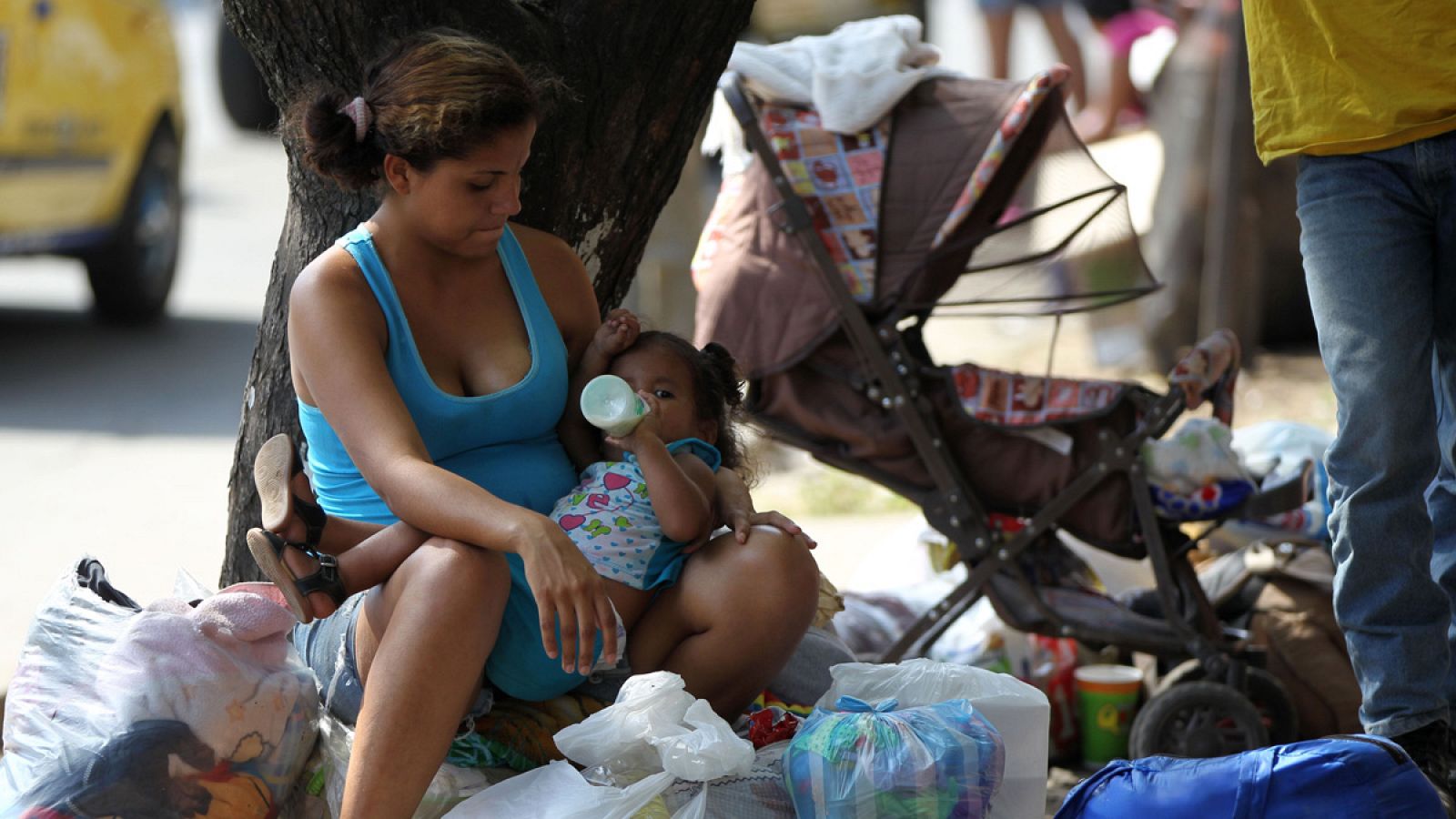 Una mujer venezolana alimenta una niña en una calle de Cali (Colombia)