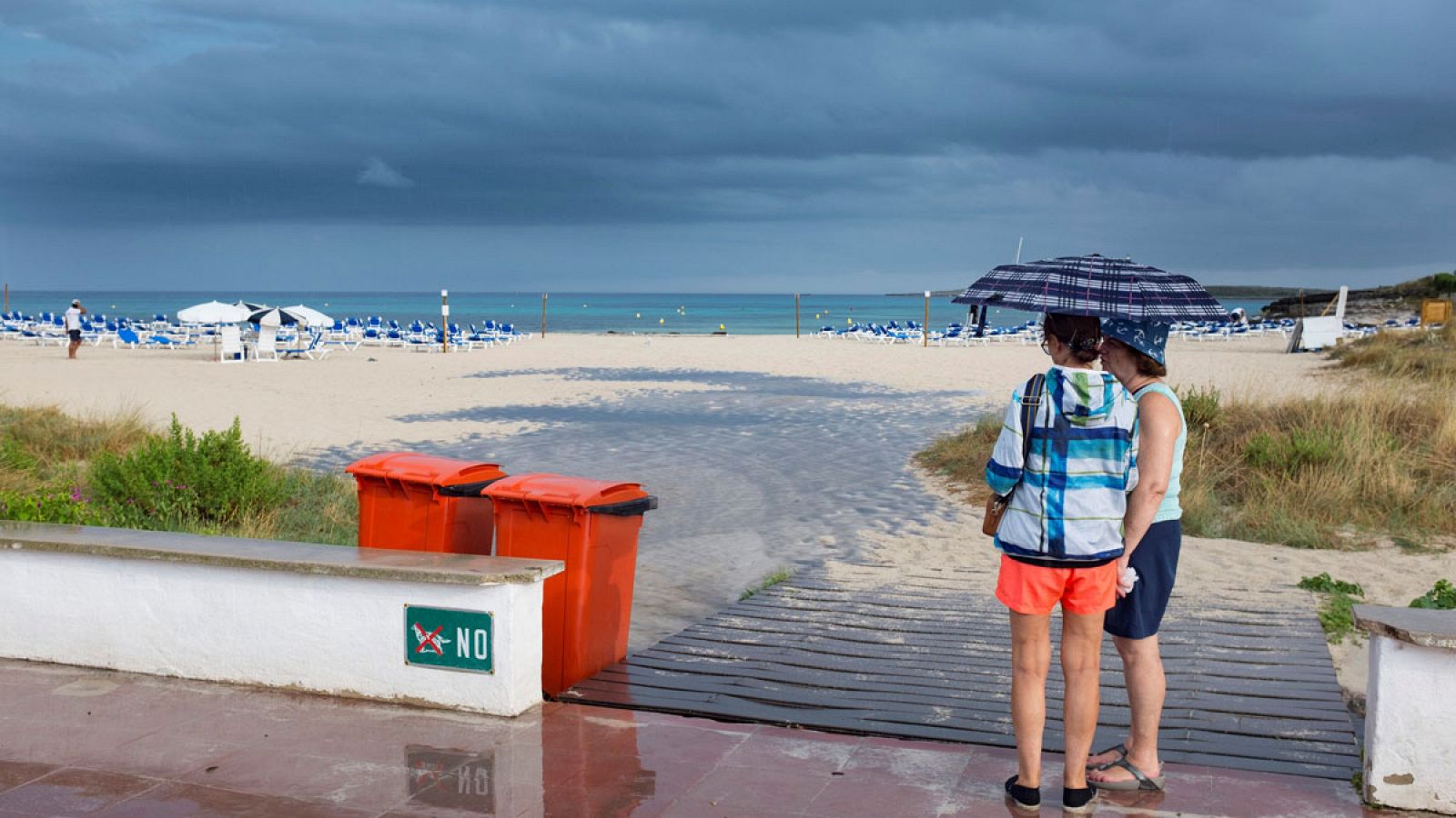 Dos mujeres se resguardan de la lluvia en Menorca