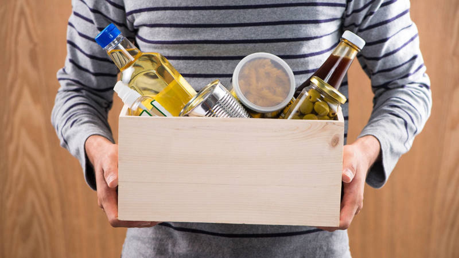  Un voluntario carga con una caja de cartón llena de alimentos no perecederos.