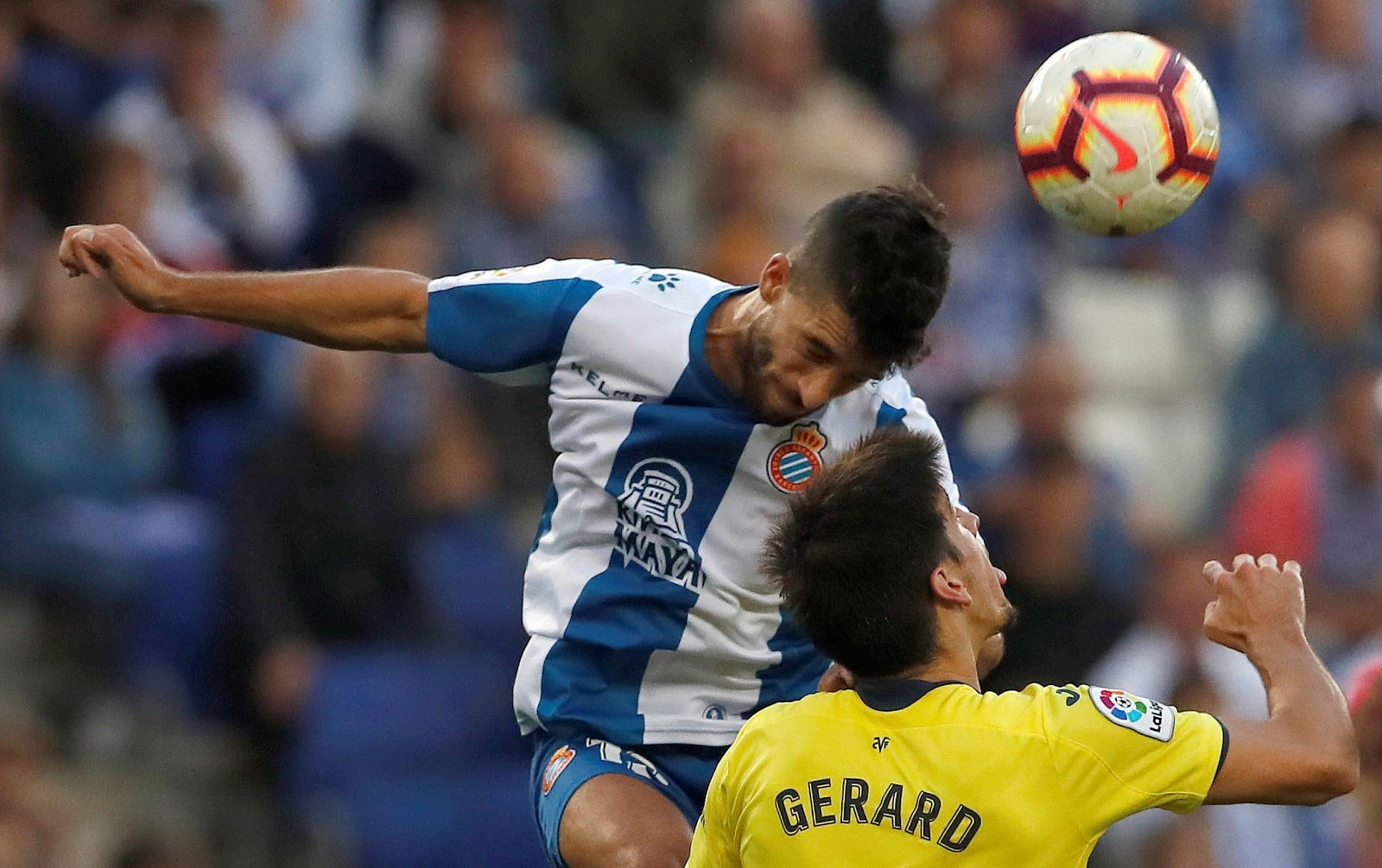 El delantero del Villarreal, Gerard Moreno (d), salta por el balón con Marc Roca, del RCD Espanyol, durante el partido de la octava jornada de Liga en Primera División que se juega esta tarde en el RCDE Stadium, en Cornellá.