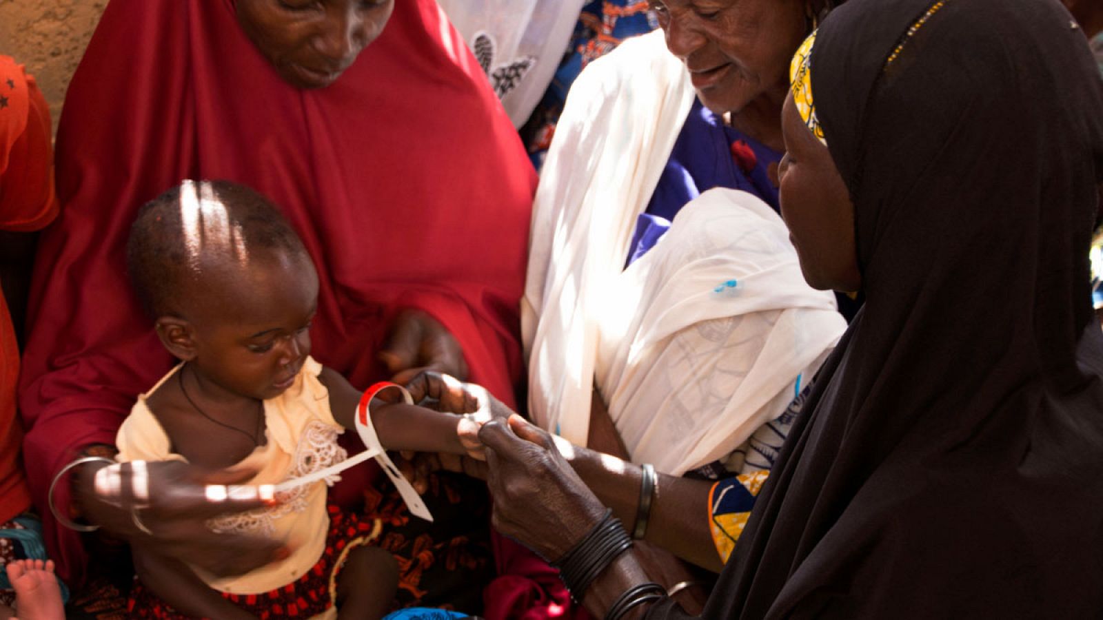 Una madre mide a su hija el perímetro del brazo con los brazaletes de medida braquial que sirven para diagnosticar precozmente la malnutrición en Lingui (Níger).