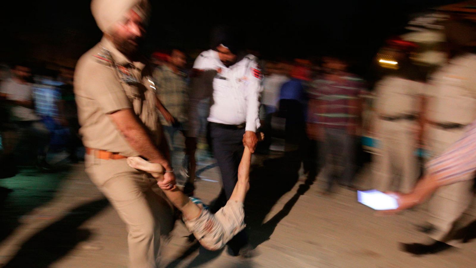 Agentes de policía transportan el cuerpo de una de las víctimas tras el accidente de tren en Amritsar (India)