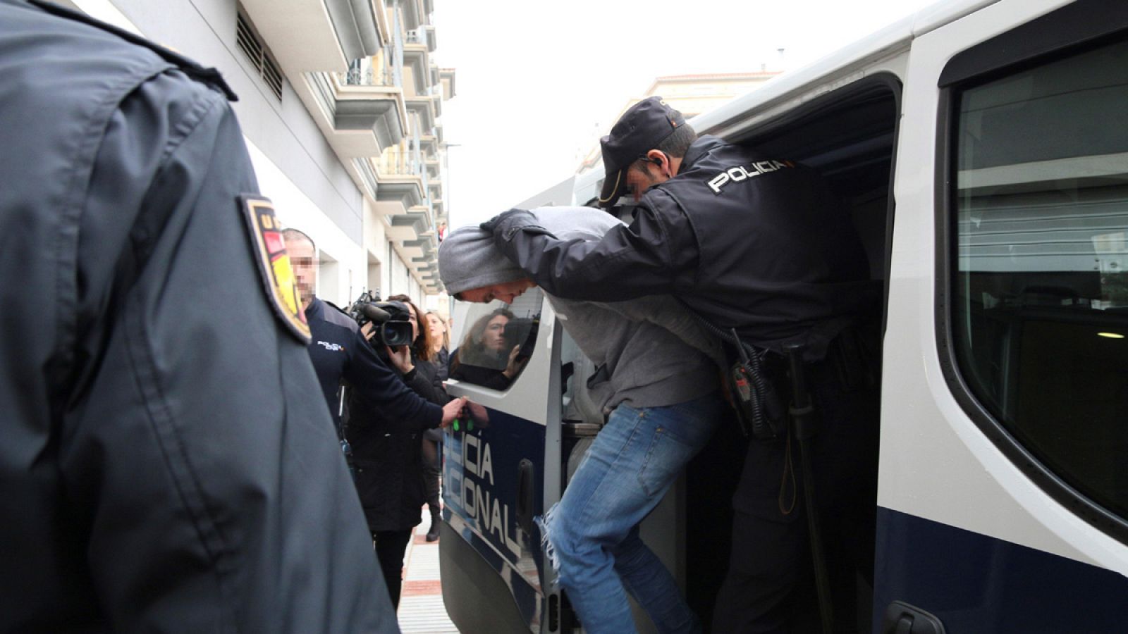 Uno de los cuatro detenidos es trasladado por agentes de la Policía Nacional