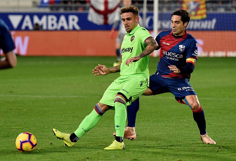 El delantero del Levante Roger (i) juega un balón ante Etxeita, del Huesca