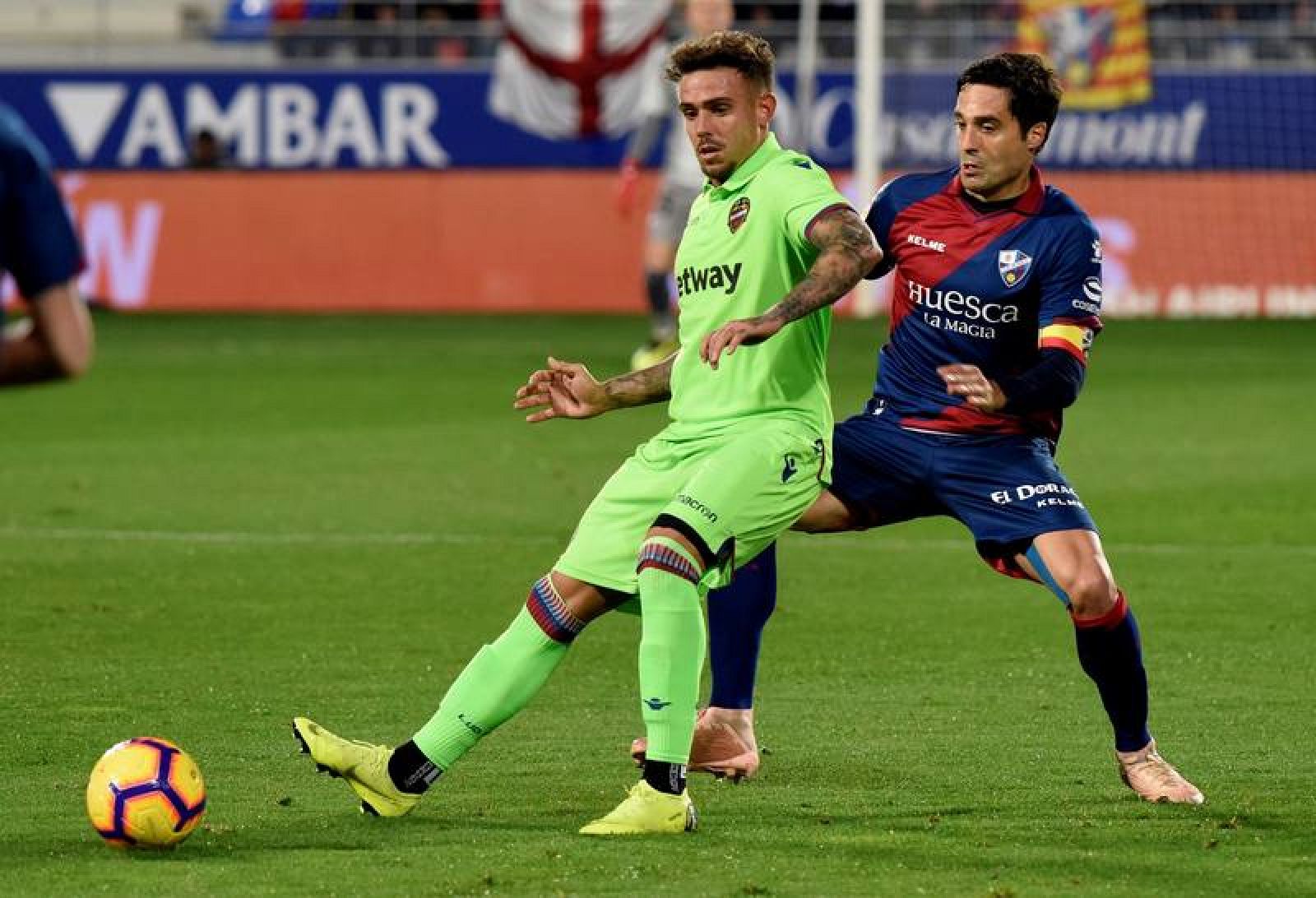 El delantero del Levante Roger (i) juega un balón ante Etxeita, del Huesca