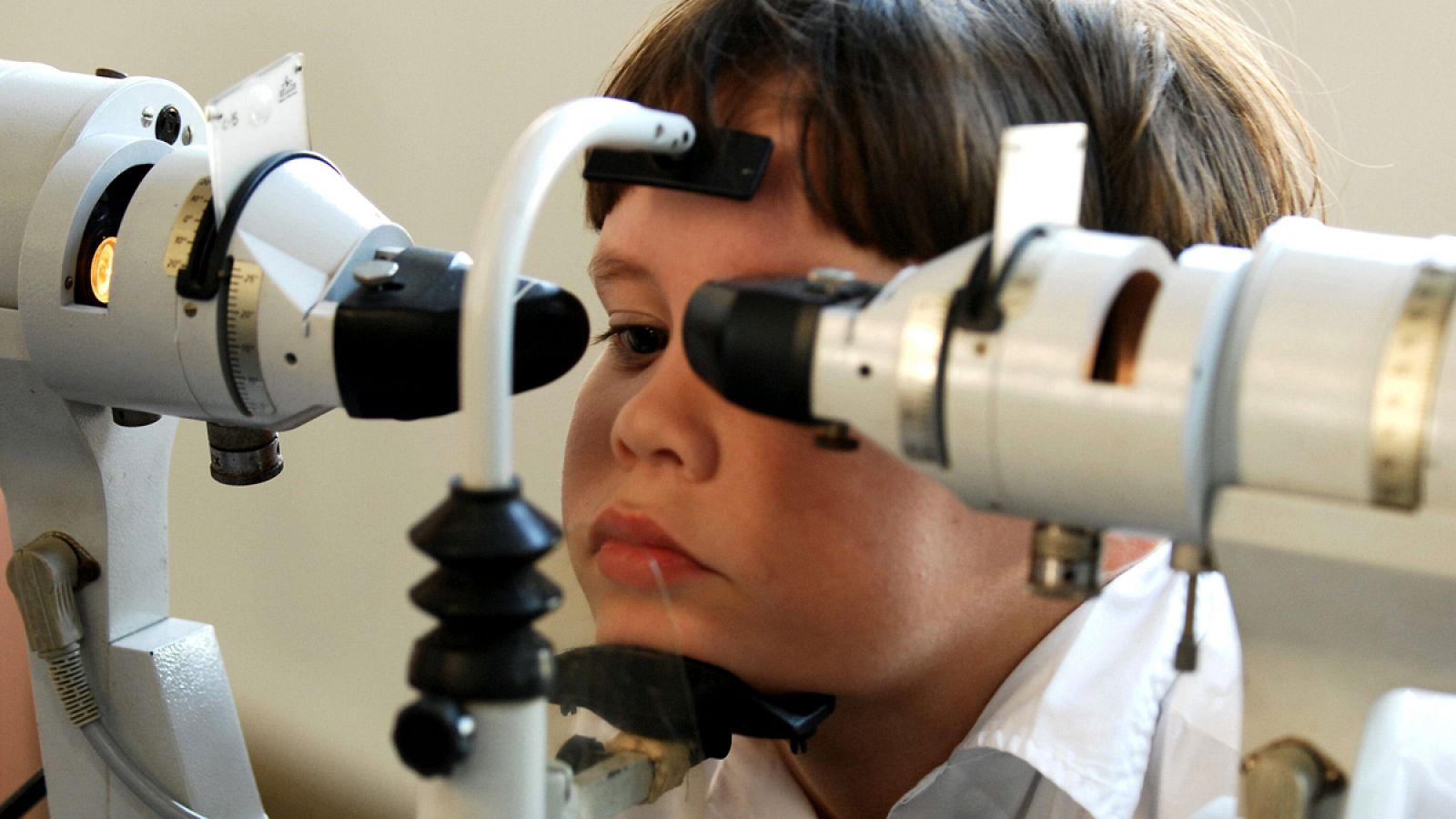 Foto de archivo de un niño con miopía severa ejercitando la vista con la ayuda de equipo médico.