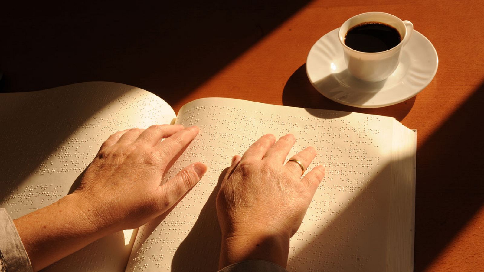 Una mujer lee un libro escrito en braille.