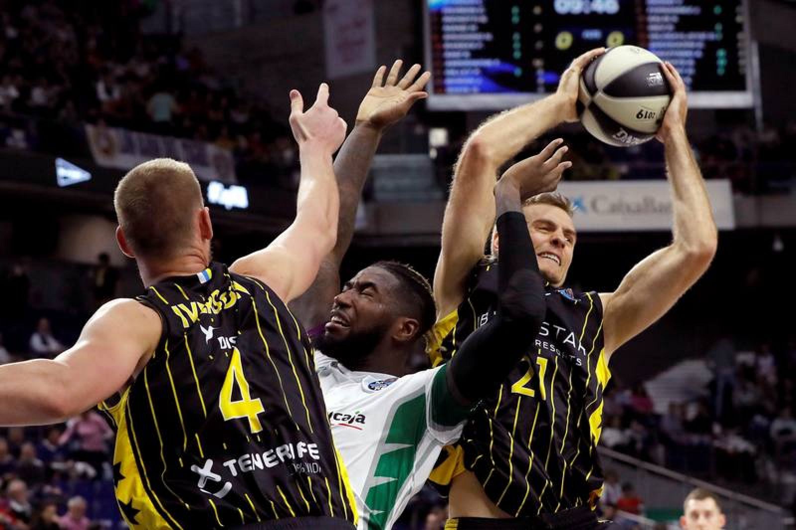 El alero estadounidense del Iberostar Tenerife, Tim Abromaitis (d), lucha, junto con su compañero el ala-pívot Colton Iverson (i), con el ala-pívot francés del Unicaja, Mathias Lessort (c), en el partido de cuartos de final de la Copa del Rey de Balo