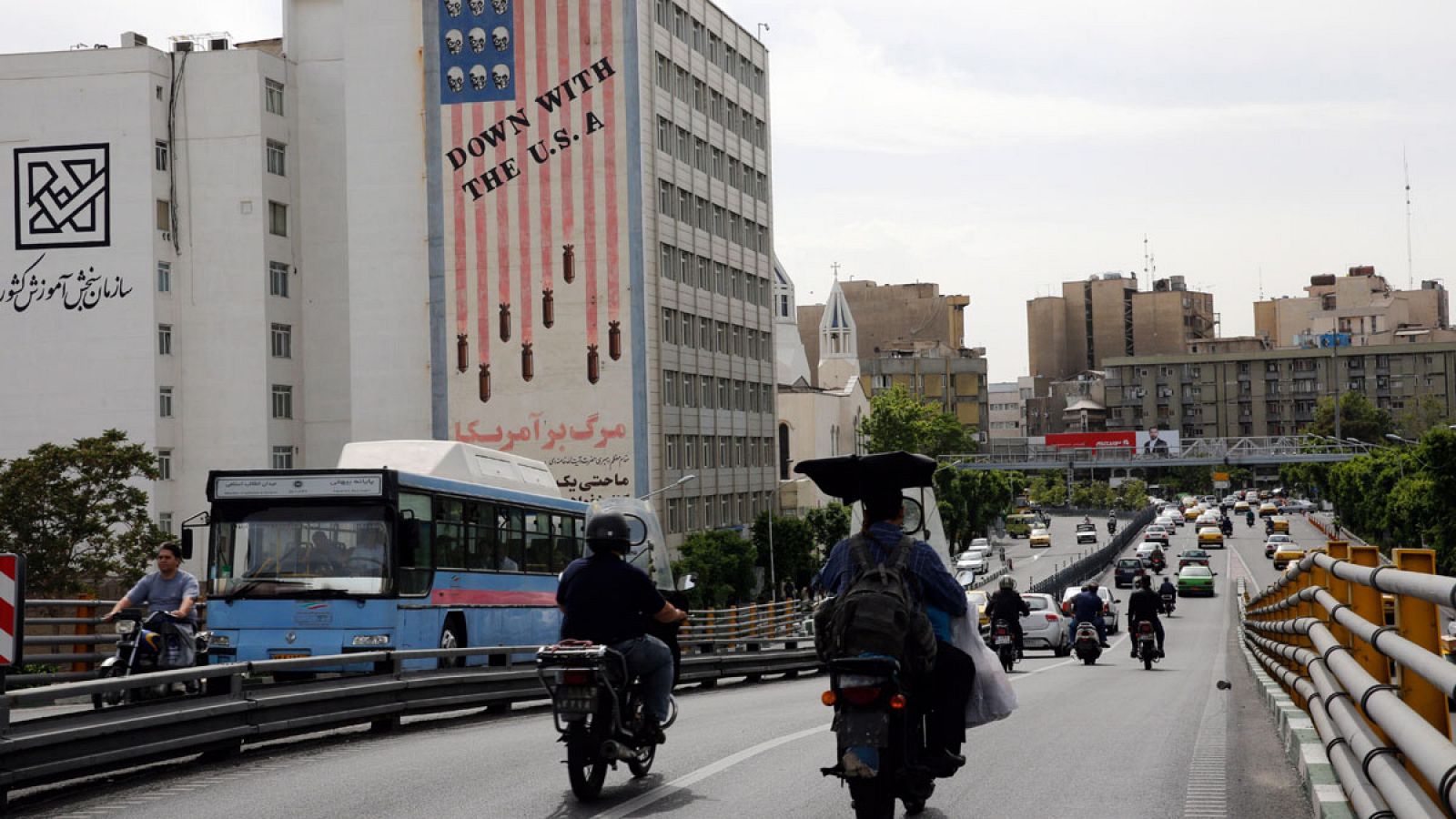 Conductores iraníes circulan junto a un edificio en el que aparece una pintada contra los Estados Unidos.