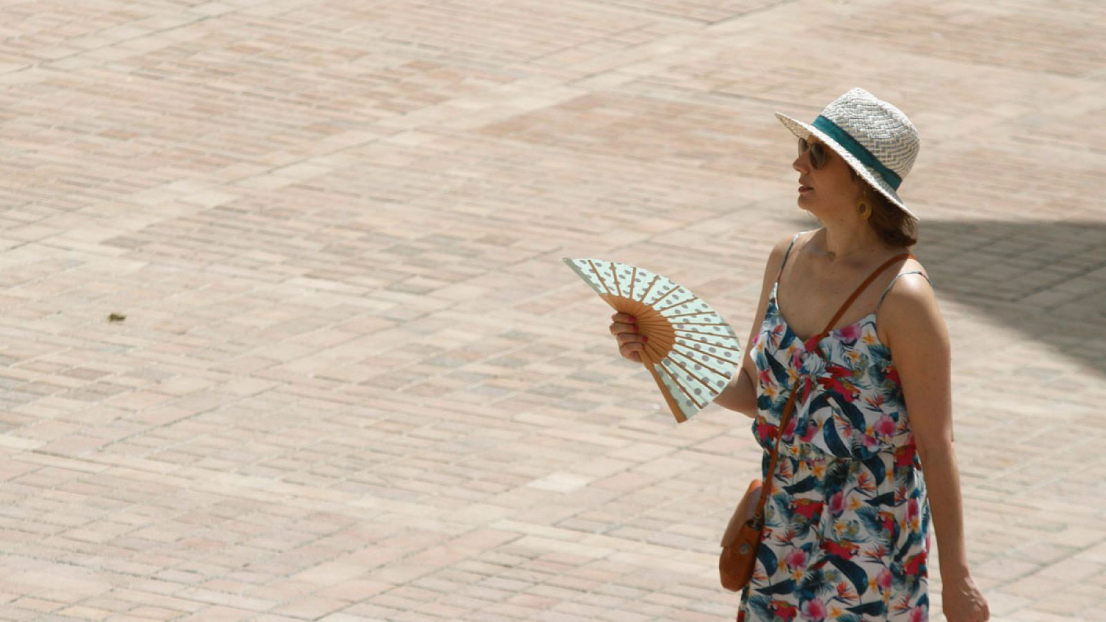 Una mujer se abanica mientras camina por la calle en una jornada en la que las previsiones apuntan al aumento de las temperaturas.