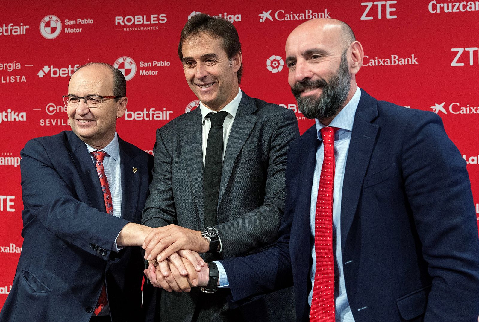 José Castro (i) y "Monchi" unen sus manos con el técnico Julen Lopetegui durante su presentación como nuevo entrenador del Sevilla FC.