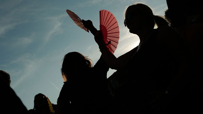 Varias mujeres combaten el calor con abanicos.