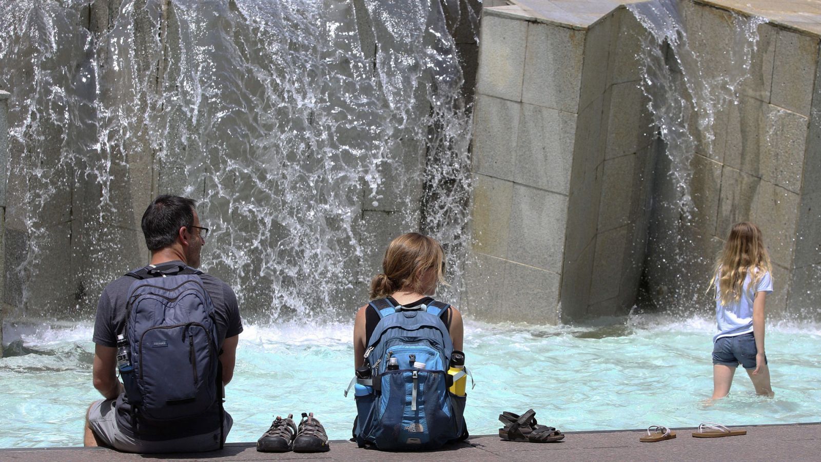 Una familia norteamericana se refresca en una de las fuentes de la Plaza del Pilar de Zaragoza