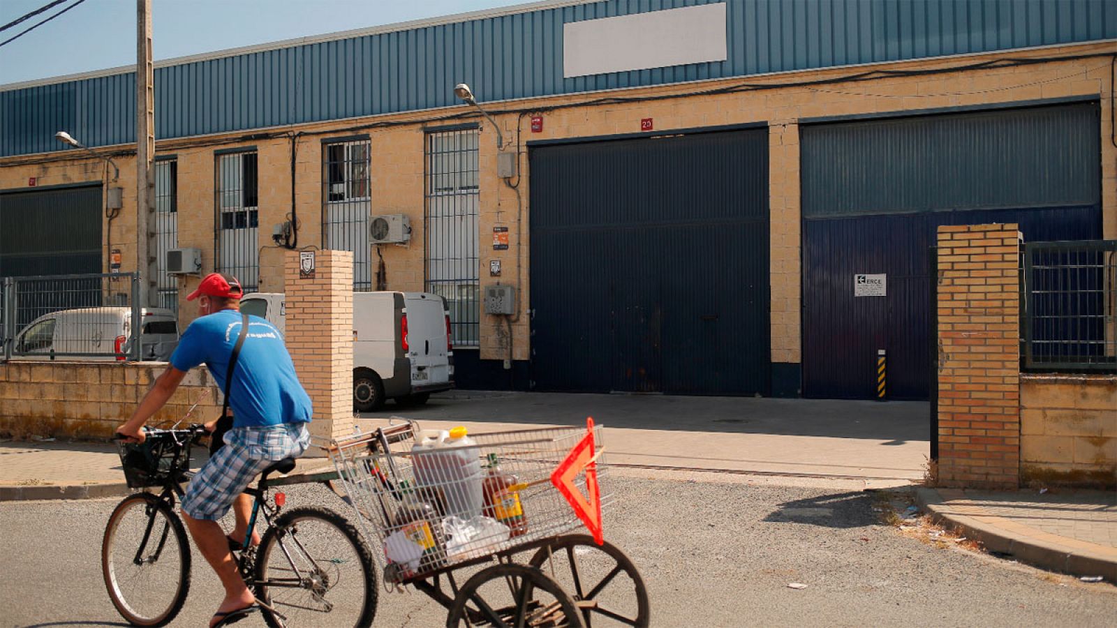 Un joven pasa en bicicleta frente a la empresa Magrudis en Sevilla