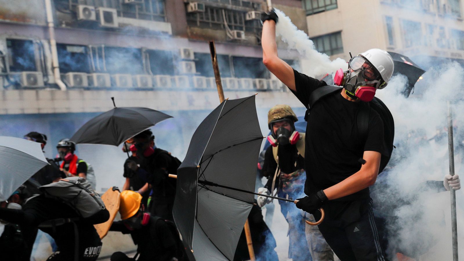 Un manifestante arroja de vuelta un bote lacrimógeno a la policía