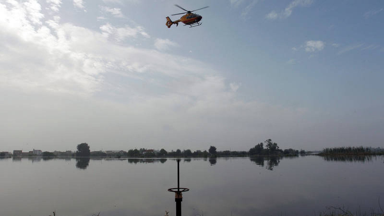 Gota fría: Un helicóptero busca en la zona donde el hombre desaparecido fue arrastrado por el agua en Dolores, Alicante.