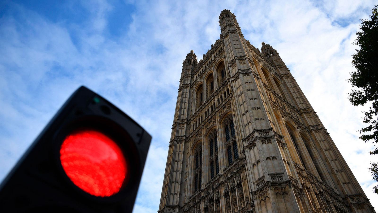 Semáforo rojo delante de la torre del parlamento británico.