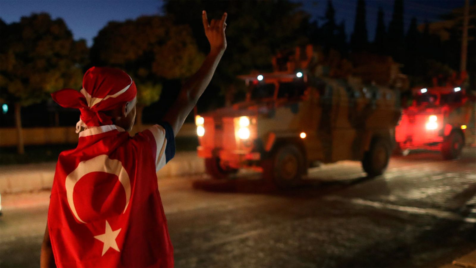 Un hombre con la bandera turca saluda a las tropas de Erdogan en plena ofensiva en el noreste de Siria