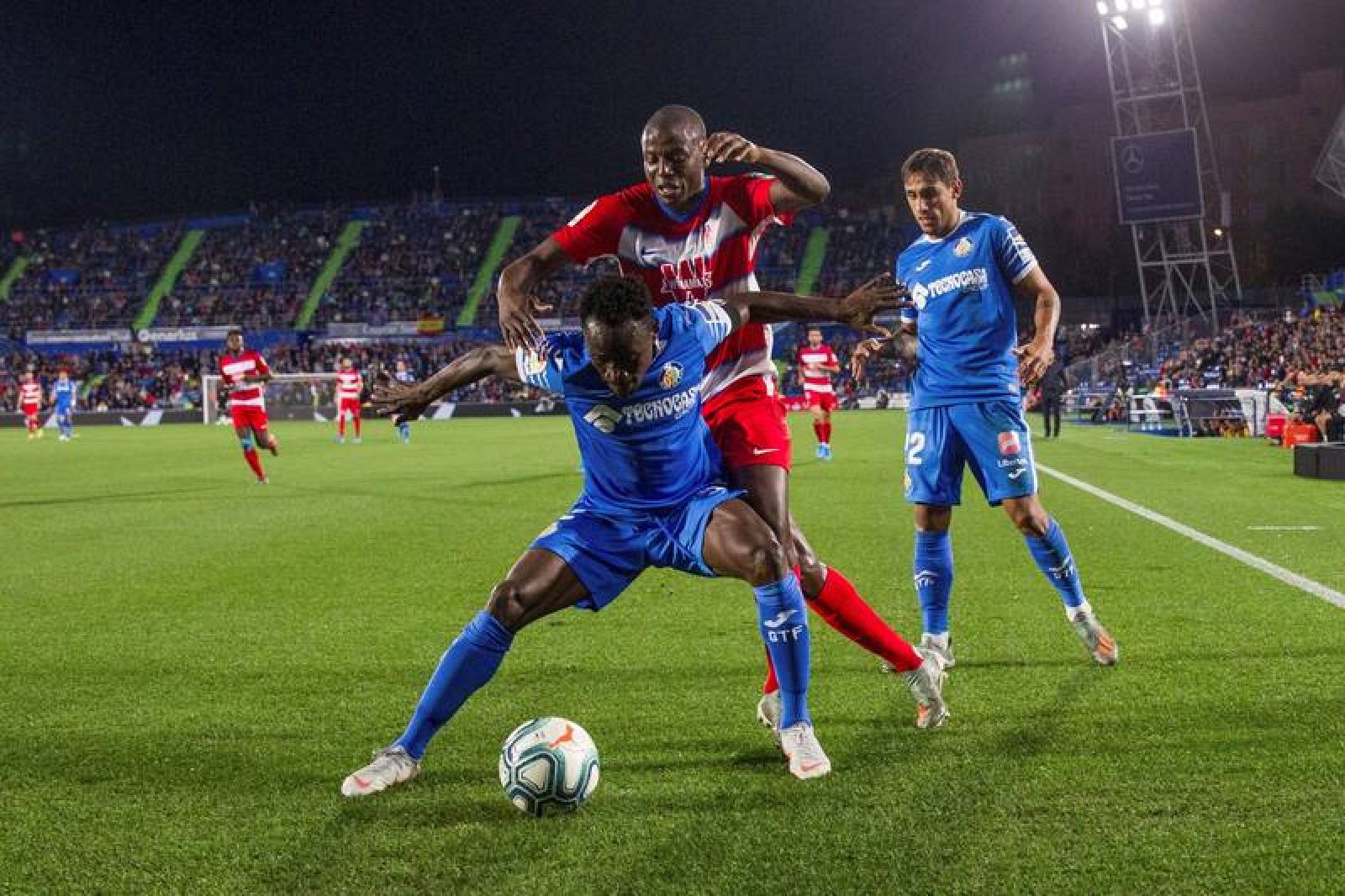 El defensa del Getafe Djené Dakonam (delante) protege el balón presionado por Darwin Machís, del Granada 