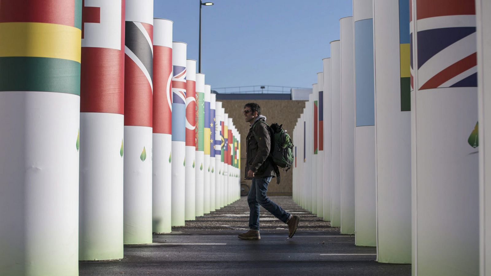 Un hombre camina entre unas columnas con las banderas de los países participantes en la COP21 de París