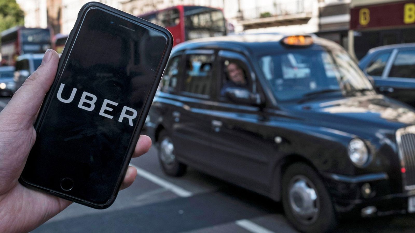 Un móvil con la aplicación de Uber frente a un taxi tradicional en Londres.  EFE/EPA/WILL OLIVER