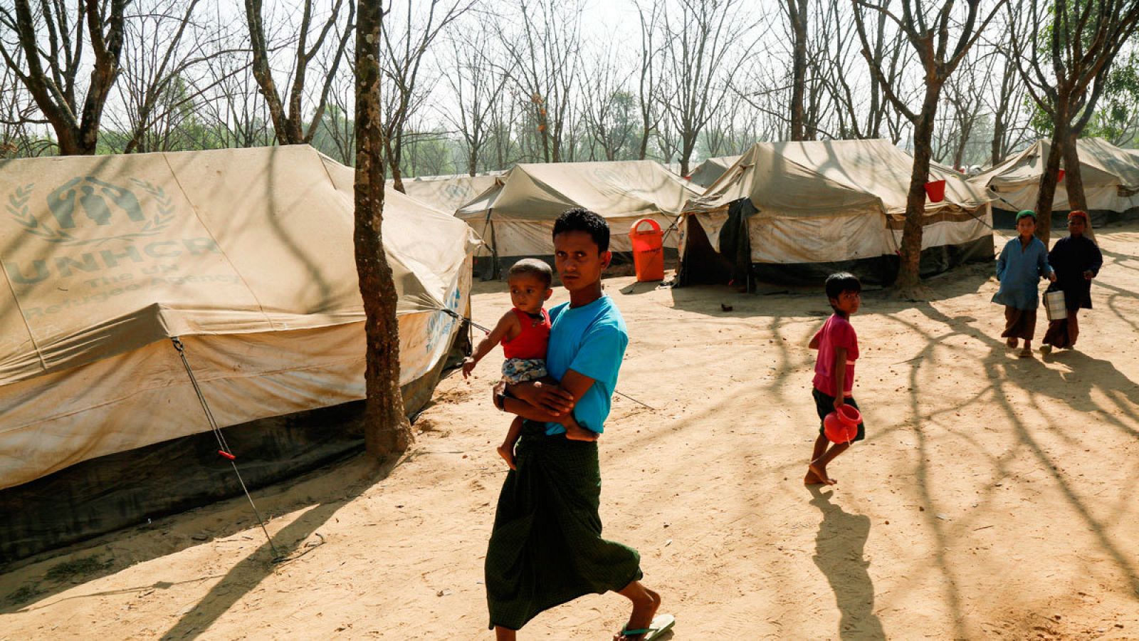 Un hombre camino con su hijo en uno de los puntos de tránsito establecidos por Naciones Unidas en Bangladesh