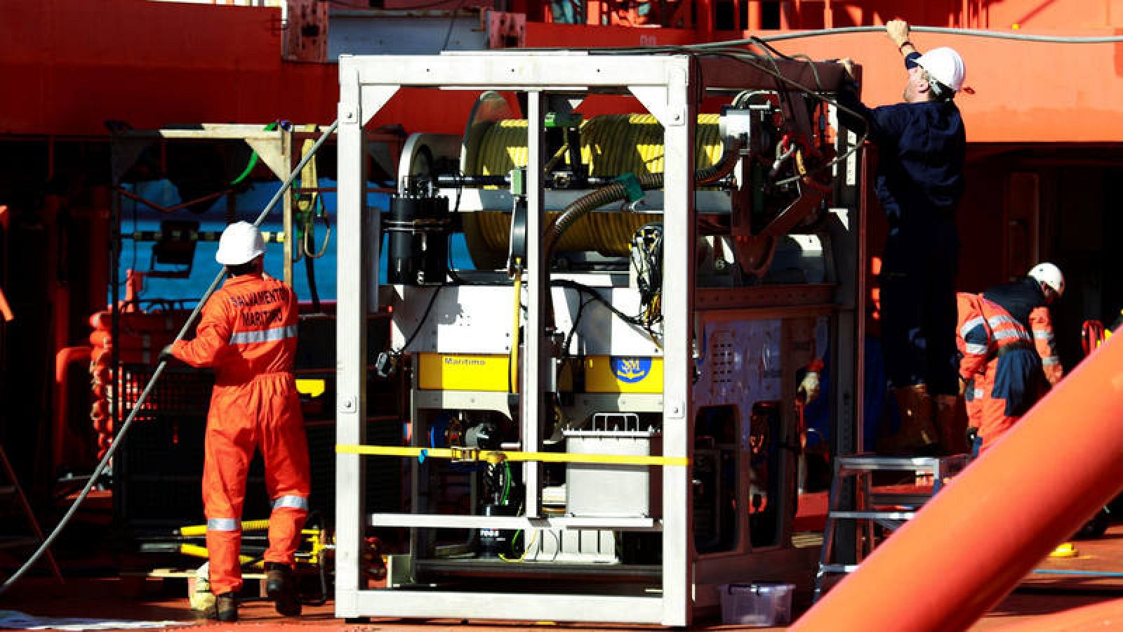 Varias personas trabajan en la instalación de un sonar y de un robot submarino en dos barcos de Salvamento Marítimo, desplegados para la búsqueda submarina del pesquero desaparecido