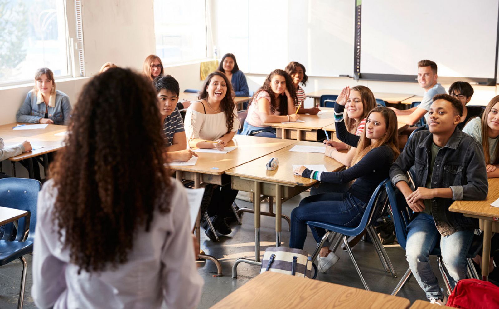 Una profesora imparte clase a un grupo de adolescentes en el aula.