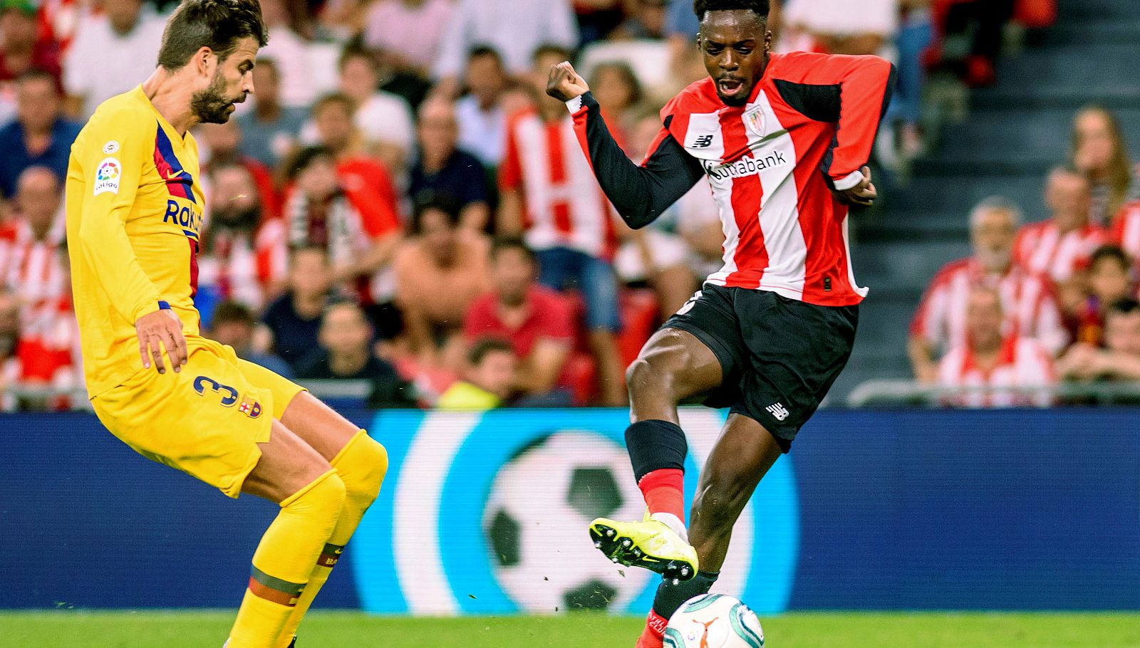 El jugador del Athletic Club de Bilbao Iñaki Williams (d) remata ante la oposición del central del FC Barcelona Gerard Piqué en el partido de Liga del 16/08/2019