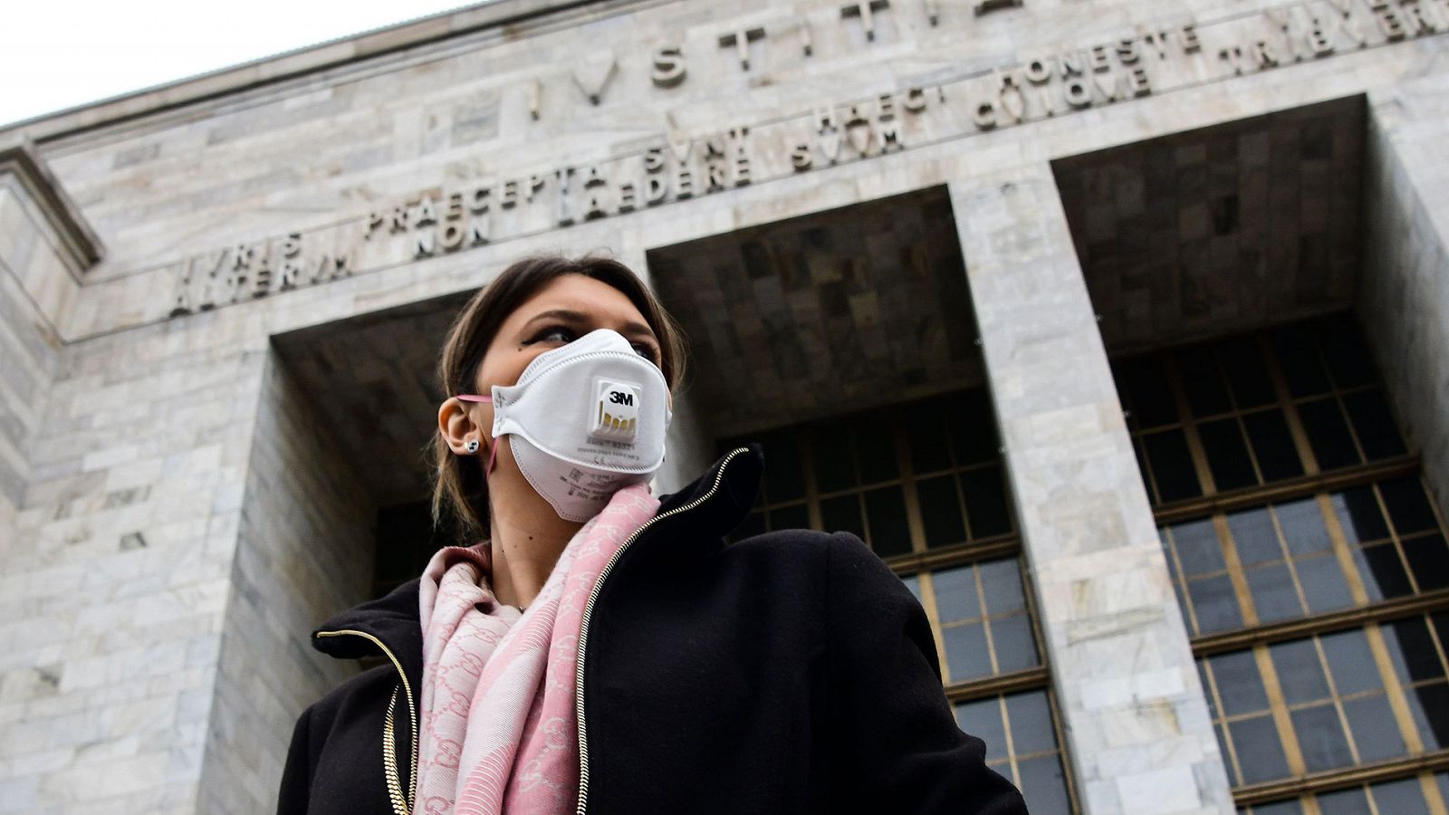 Una mujer con mascarilla camina frente al Palacio de Justicia de Milán.
