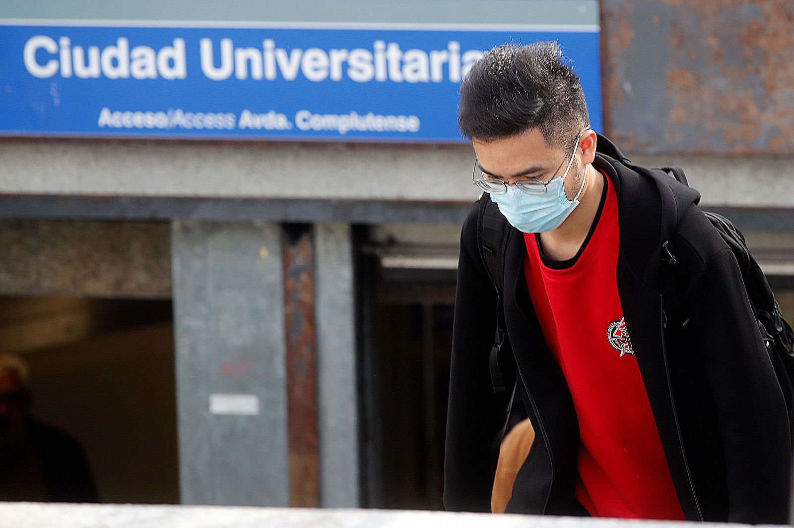 Un joven con mascarilla en el acceso a la estación de metro de Ciudad Universitaria