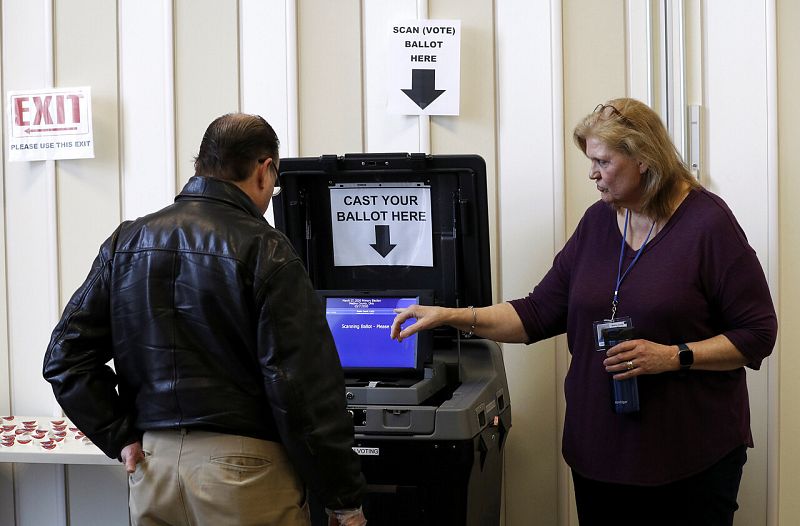 Una voluntaria ayuda a un hombre a emitir su voto anticipado en Medina, Ohio