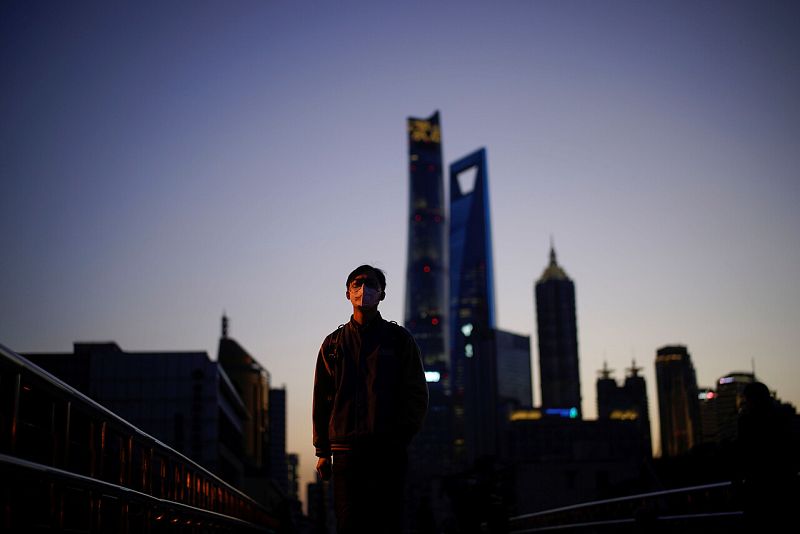 Un hombre usa una máscara en el distrito financiero de Lujiazui en Shanghái, China