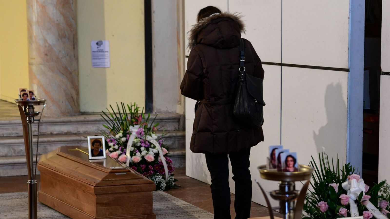 Una mujer frente a un ataud en una iglesia de Italia, donde hay miles de muertos por el coronavirus.